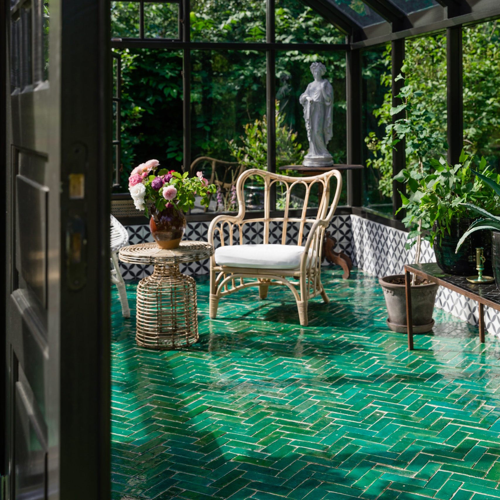 Indoor garden with green tiled floor, wicker chairs, and decorative elements.