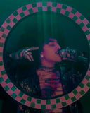 Person with tattoos holding a glass in front of a checkered frame