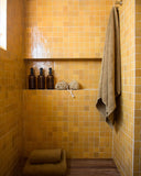 Bathroom with yellow tiled walls, a towel, and bottles on a shelf.