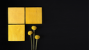 Three yellow square tiles with a small arrangement of yellow flowers on a black background