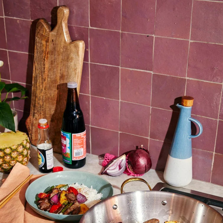 Person cooking stir-fry in a pan on a stove with a kitchen background.