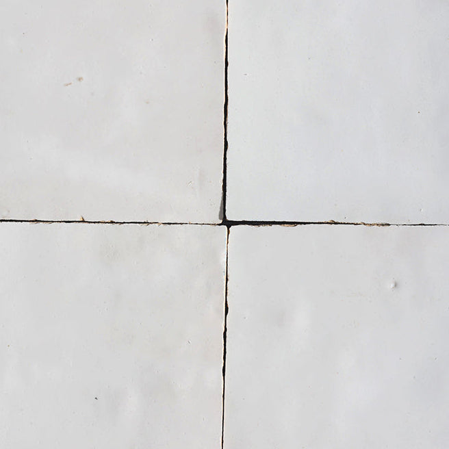 Close-up of four square tiles with visible grout lines on a white background